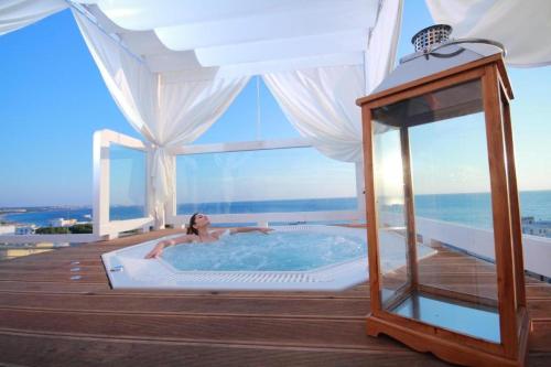 a woman laying in a hot tub on a deck at Hotel Miramare in Gallipoli