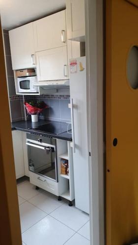 une cuisine avec des armoires blanches et un comptoir noir dans l'établissement Appartement F3 idéal JO proche de paris, à Épinay-sur-Seine