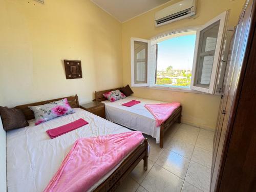 two beds in a room with a window at Villa marina 5 first row on lake 5 bed rooms ac in El Alamein