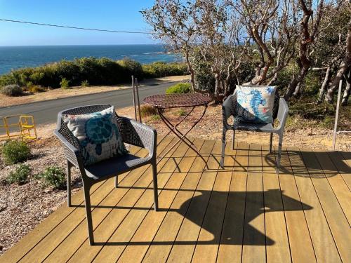two chairs and a table on a deck with the ocean at Windance in Augusta