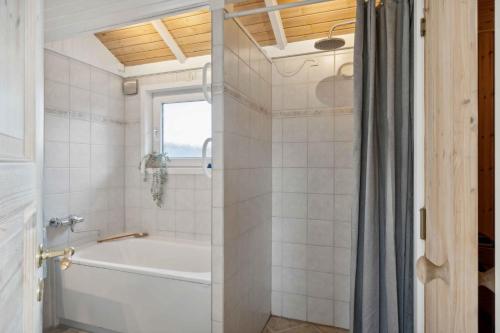 y baño blanco con bañera y ducha. en Summer House With Sauna Near Flle Strand,, en Rønde