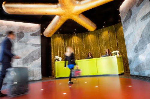 a woman walking through a lobby with luggage at Glam Milano in Milan
