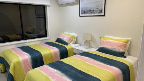 two beds sitting next to a window in a room at HEATed Pool, Lake & Beach, Luxury 5 B/R House in Lake Illawarra