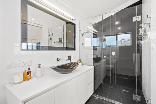 y baño con lavabo y ducha acristalada. en HEATed Pool, Lake & Beach, Luxury 5 B/R House, en Lake Illawarra