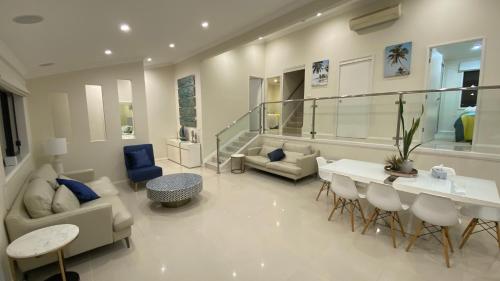 a living room with a couch and a table and chairs at HEATed Pool, Lake & Beach, Luxury 5 B/R House in Lake Illawarra