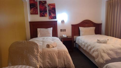 Habitación de hotel con 2 camas y teléfono en CORONA, en Puno