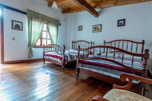 two beds in a room with wooden floors and a window at Hacienda Venta de Guadalupe in La Venta