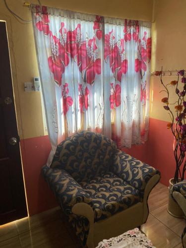 a chair in front of a window with red flowers at Lusignan selfcontain apart two br and onebath in Georgetown