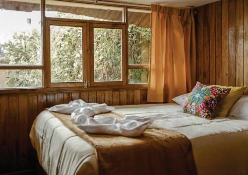 1 dormitorio con 1 cama grande y 2 ventanas en WARM AND CENTRAL HOUSE WITH SPECTACULAR VIEW OF CUSCO en Cusco