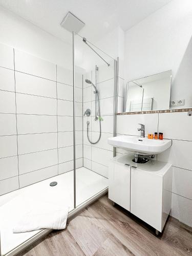a white bathroom with a shower and a sink at FEWO Gleis 1 in Oberstaufen