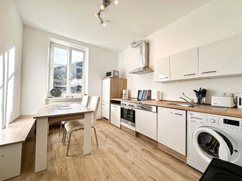 a kitchen with a table and a laundry machine at FEWO Gleis 1 in Oberstaufen
