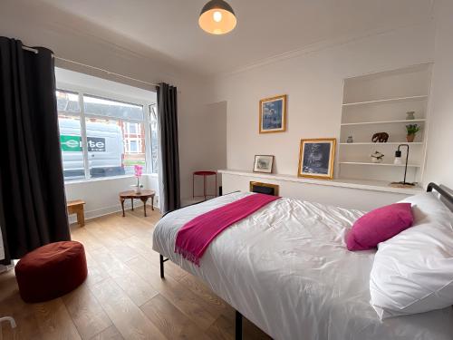 a bedroom with a bed with pink and white pillows at 4-Bedroom home - Perfect for those working in Bridgend - By Tailored Accommodation in Bridgend