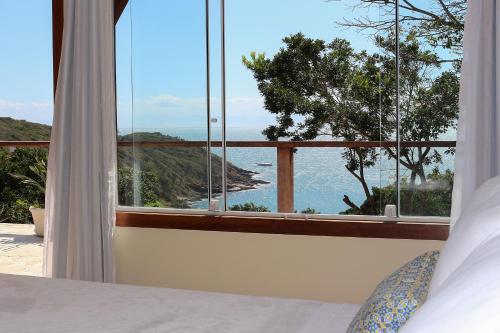 a bedroom with a large window with a view of the ocean at Pousada La Dolce Vita in Búzios