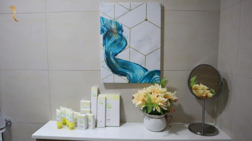 Chalet 2BR Duplex Apartment في أبوظبي: حمام مع مرآة والزهور على منضدة