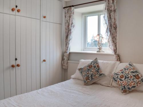 a bedroom with a bed with two pillows and a window at Mitsys Cottage in Darley