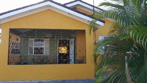 a yellow house with a window and a palm tree at LaMaison in Ocho Rios