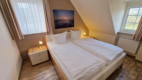 ein kleines Schlafzimmer mit einem Bett mit weißer Bettwäsche und Kissen in der Unterkunft Haus Theo Luise Whg 03 in Sankt Peter-Ording