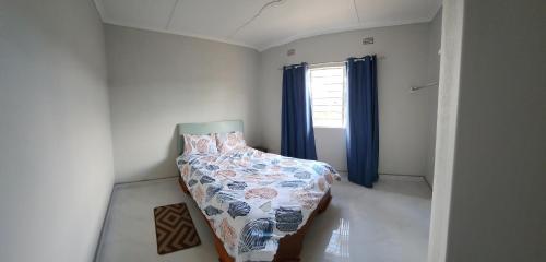 Schlafzimmer mit einem Bett und einem Fenster mit blauen Vorhängen in der Unterkunft Essy's in Musele