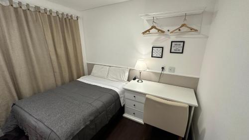 a small bedroom with a bed and a desk at Apartamento inteiro no 15º andar próximo ao aeroporto de Guarulhos GRU in Guarulhos