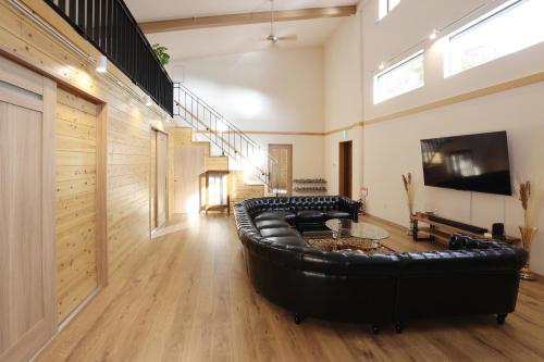 a large living room with a black leather couch at 4S resort eeyan in Ikisue