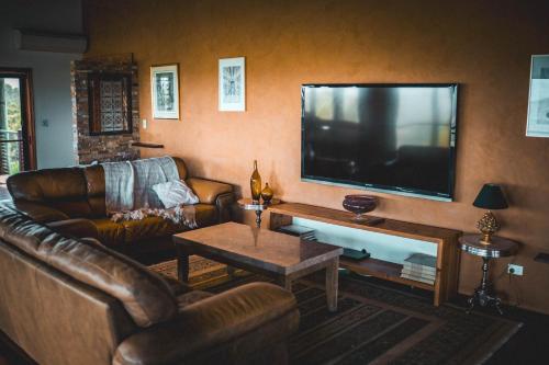 a living room with leather furniture and a flat screen tv at Luxurious Hinterland Guest House with HEATED POOL Sleeps 10 Brisbane Scenic Rim Gold Coast in Canungra