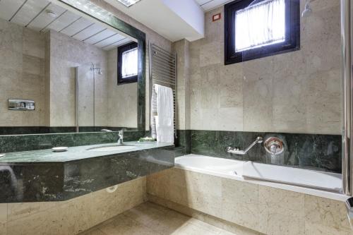 bagno con vasca, lavandino e specchio di Borgo Palace Hotel a Sansepolcro
