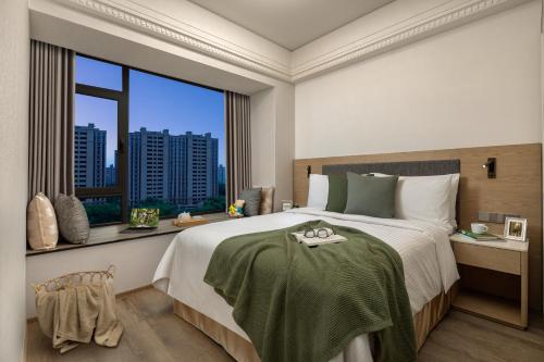 a bedroom with a large bed and a large window at Somerset Star River Minhang Shanghai in Shanghai