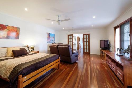 a bedroom with a bed and a couch and a television at Your Home at Southside Central - Family friendly. in Bundaberg