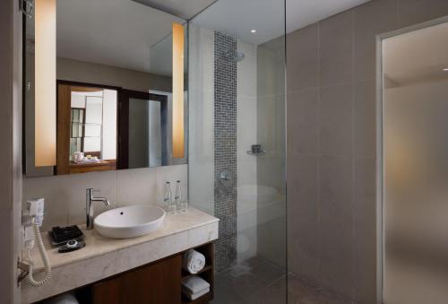 La salle de bains est pourvue d'un lavabo et d'une douche en verre. dans l'établissement Taksu Sanur Hotel, à anur