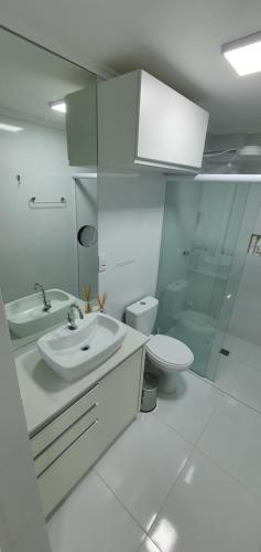 La salle de bains blanche est pourvue d'un lavabo et de toilettes. dans l'établissement Amplio apartamento a cuadra del mar, cerca de todo, à Balneário Camboriú