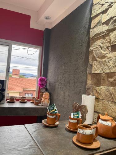 a table with cups of coffee and a stone wall at Farolito de Luz Apart in Salta