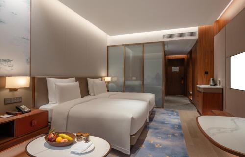 a bedroom with a bed and a bowl of fruit on a table at Suzhou International Conference Hotel in Suzhou