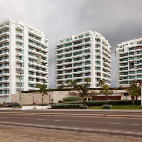 two tall buildings with palm trees in front of a street at Hospedaje,Cartagena,Terraza San Sebastián in Cartagena de Indias