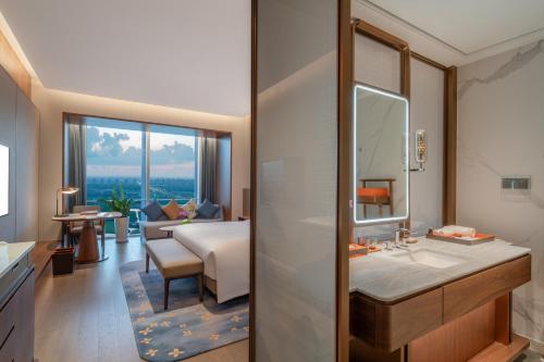 een badkamer met een wastafel en een slaapkamer met een bed bij Suzhou International Conference Hotel in Suzhou