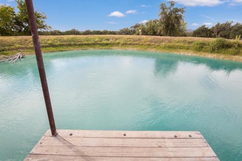 a wooden dock in a pond with blue water at Hill Country Mirage in Bandera