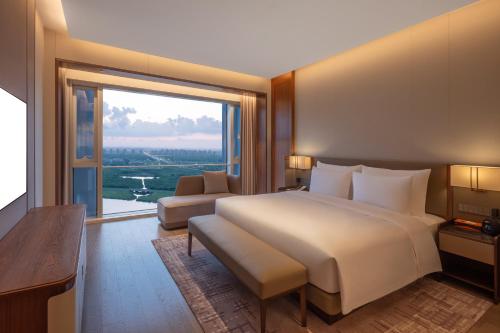 a bedroom with a large bed and a large window at Suzhou International Conference Hotel in Suzhou