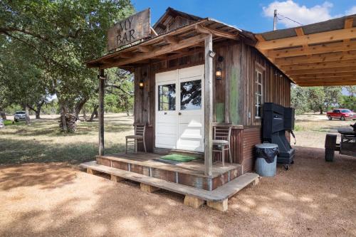 a small wooden cabin with a porch and a door at Hill Country Mirage in Bandera