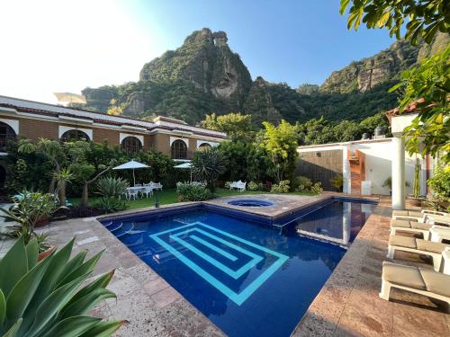 a house with a swimming pool with mountains in the background at Hotel Hacienda Ventana del Cielo in Tepoztlán