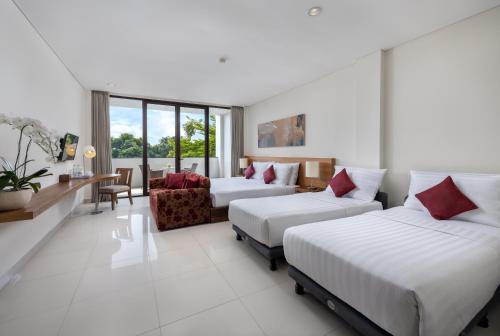 サヌールにあるタクス サヌール ホテルのベッド2台とソファが備わるホテルルームです。
