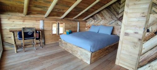 a bedroom in a log cabin with a bed and a desk at Cabaña Lato_puzhio in Chordeleg