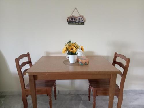 a wooden table with two chairs and a vase of flowers on it at D'Mentari Ocean View Resort Studio in Kampong Tanah Merah