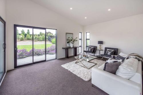 sala de estar con sofá blanco y ventana grande en Rolleston Lodge en Christchurch
