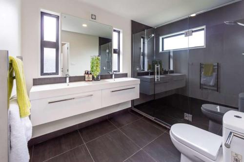 y baño con lavabo, aseo y espejo. en Rolleston Lodge, en Christchurch