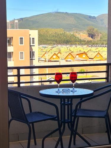 two glasses of wine sitting on a table on a balcony at Alojamiento San Pedro de la Paz in San Pedro de la Paz