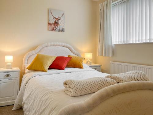a bedroom with a white bed with colorful pillows at Rosings in Bradfield