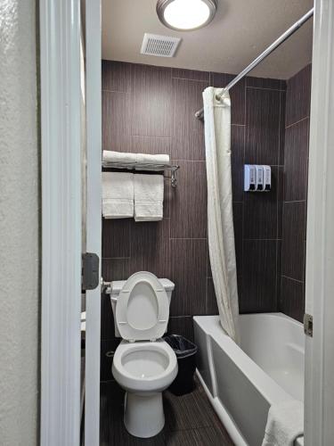 a bathroom with a toilet and a tub and a sink at Canyon Inn Flagstaff in Flagstaff