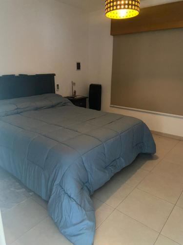 Schlafzimmer mit einem Bett mit blauer Decke in der Unterkunft La josefina in Villa María