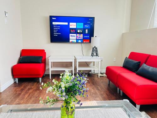 a living room with two red couches and a tv at Basement unit with 2 bedrooms, bath and living area in Lower Sackville