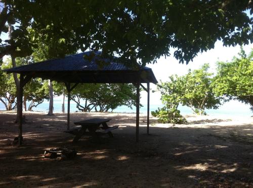 a picnic table and a blue umbrella on the beach at Caraibe Créol' Keys in Port-Louis