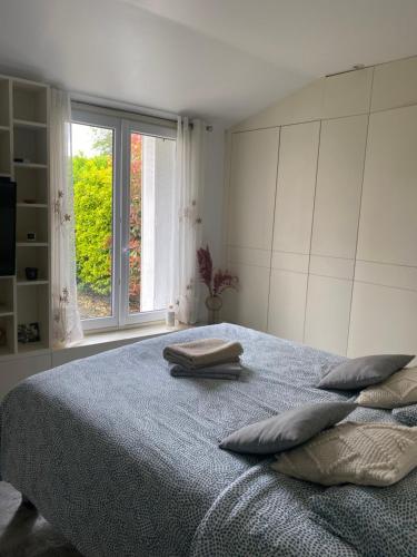 een slaapkamer met een bed met 2 kussens en een raam bij Le Saint-Brice de Paris in Saint-Brice-sous-Forêt